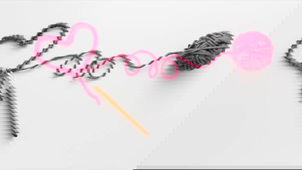 Heart shape and wool ball on white background