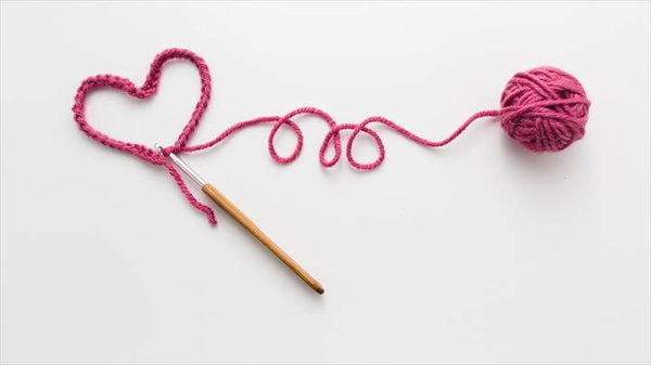 Heart shape and wool ball on white background